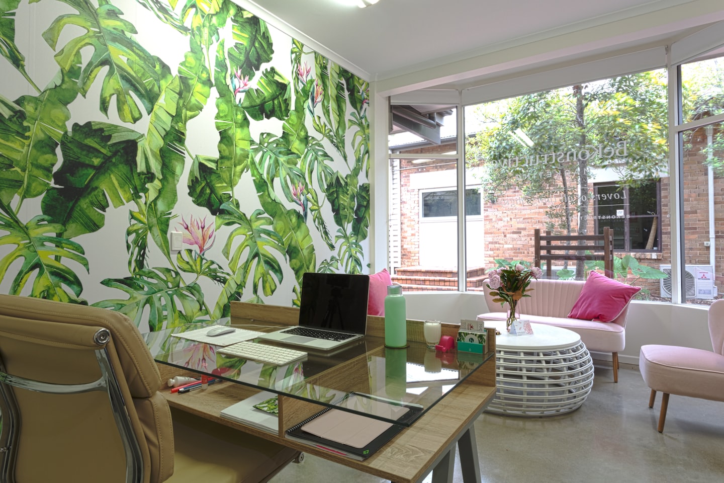 Modern office with a wooden desk and floral wall mural.