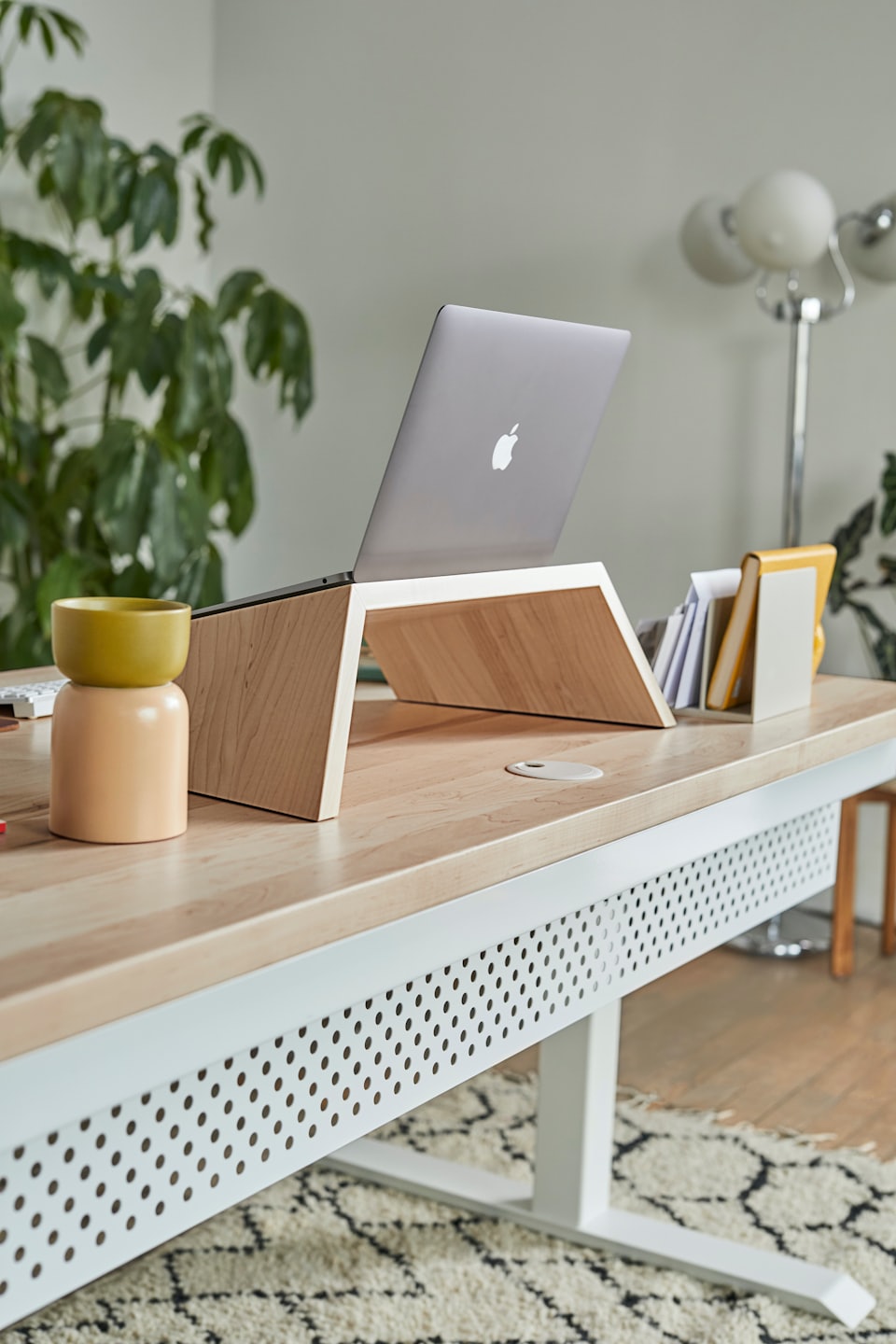 Laptop on a light wood stand on a modern desk.